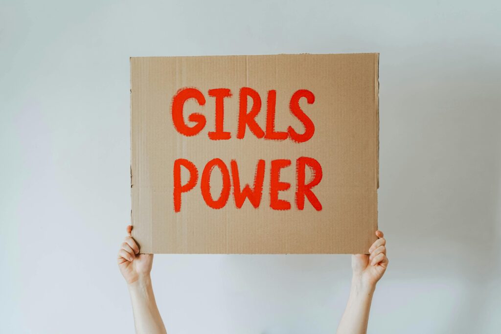 Cardboard sign with 'Girls Power' slogan held up by two hands, symbolizing feminism.